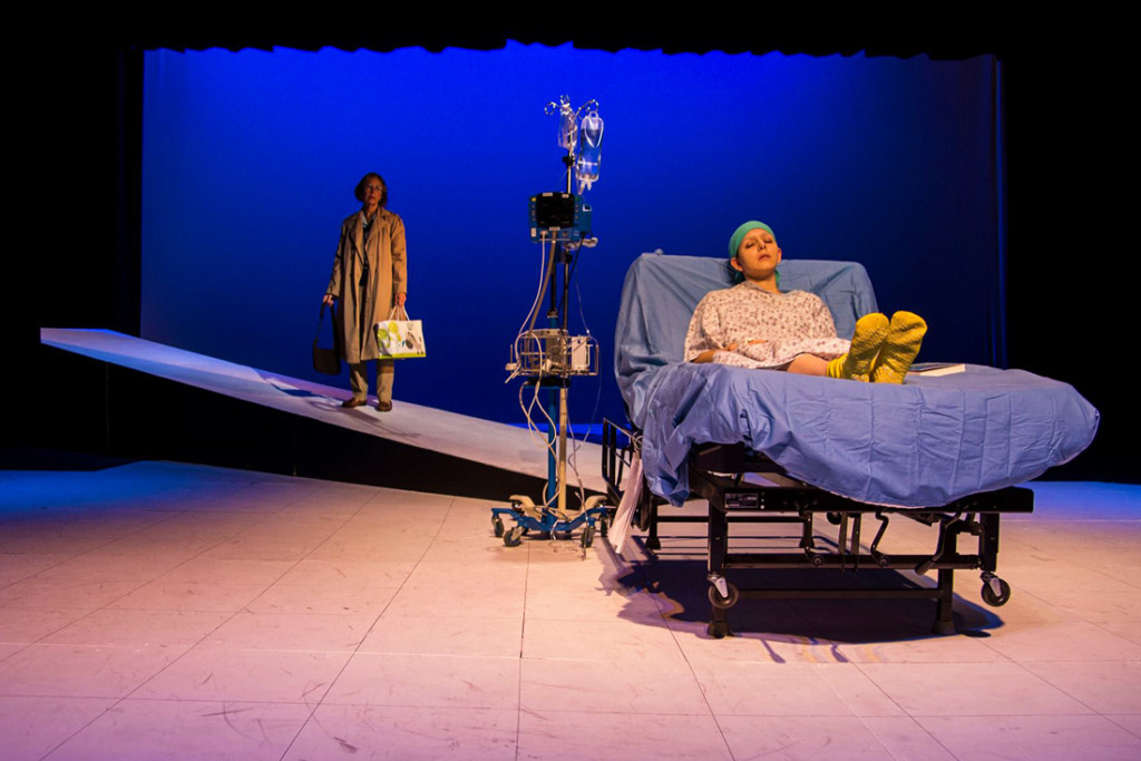 Vivian Bearing (portrayed by Ana Laura Chavez) lays unconscious in a hospital bed while her literature mentor, E.M. Ashford (portrayed by Kathy Raines) enters the scene. The production of “Wit” opened the 53rd season of the Camille Playhouse in Brownsville./P hoto Courtrtesy Camille Playhouse