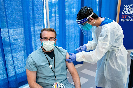 David Barrera, un estudiante de segundo año de la Facultad de Medicina de UTRGV, se prepara para inyectar al Dr. Brandon Cantazaro, director del programa de la Facultad de Medicina de UTRGV y profesor de medicina interna, con su segunda dosis de la vacuna contra el COVID-19 de Pfizer