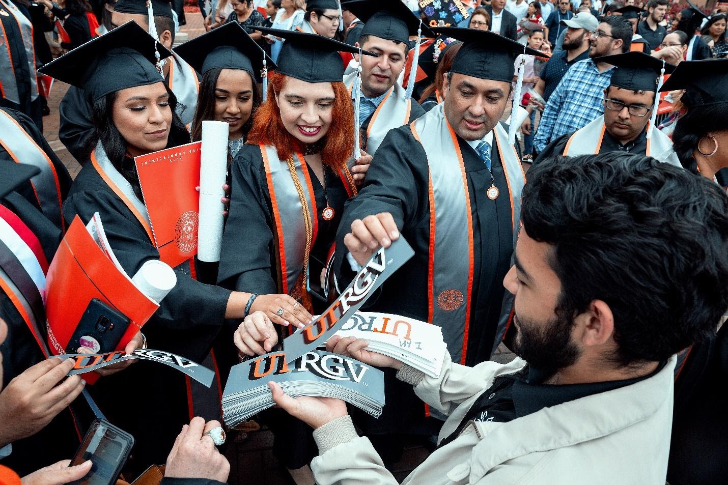 Graduating seniors grab university bumper stickers during the May 11, 2019, Spring Commencement held at the McAllen Convention Center. Paul Chouy/UTRGV Marketing and Communications