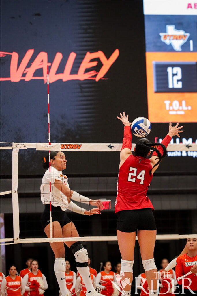 Vaqueros senior right-side hitter Perris Key spikes past Raiders graduate student outside hitter Mia Wesley during tonight’s sold-out game in the UTRGV Fieldhouse on the Edinburg campus. The first home game of the season drew 2,771 attendees. Abigail Ollave/THE RIDER