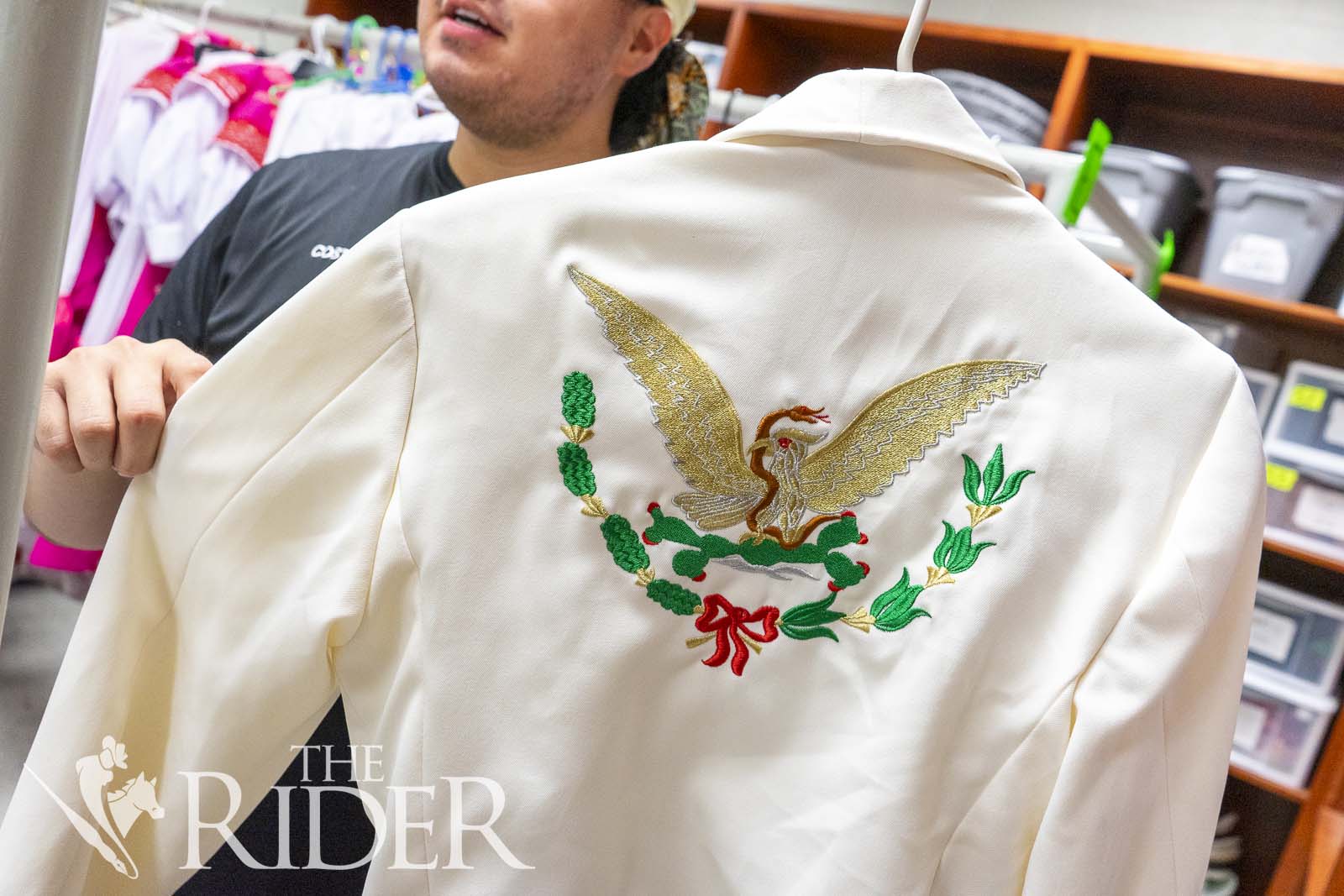 Dance senior Juan Jose Gonzalez holds a beige, embroidered jacket from Colima, Mexico. Gonzalez assists the costume department in making critical decisions of what ensembles to feature in folklórico dance performances. Eduardo Escamilla/THE RIDER