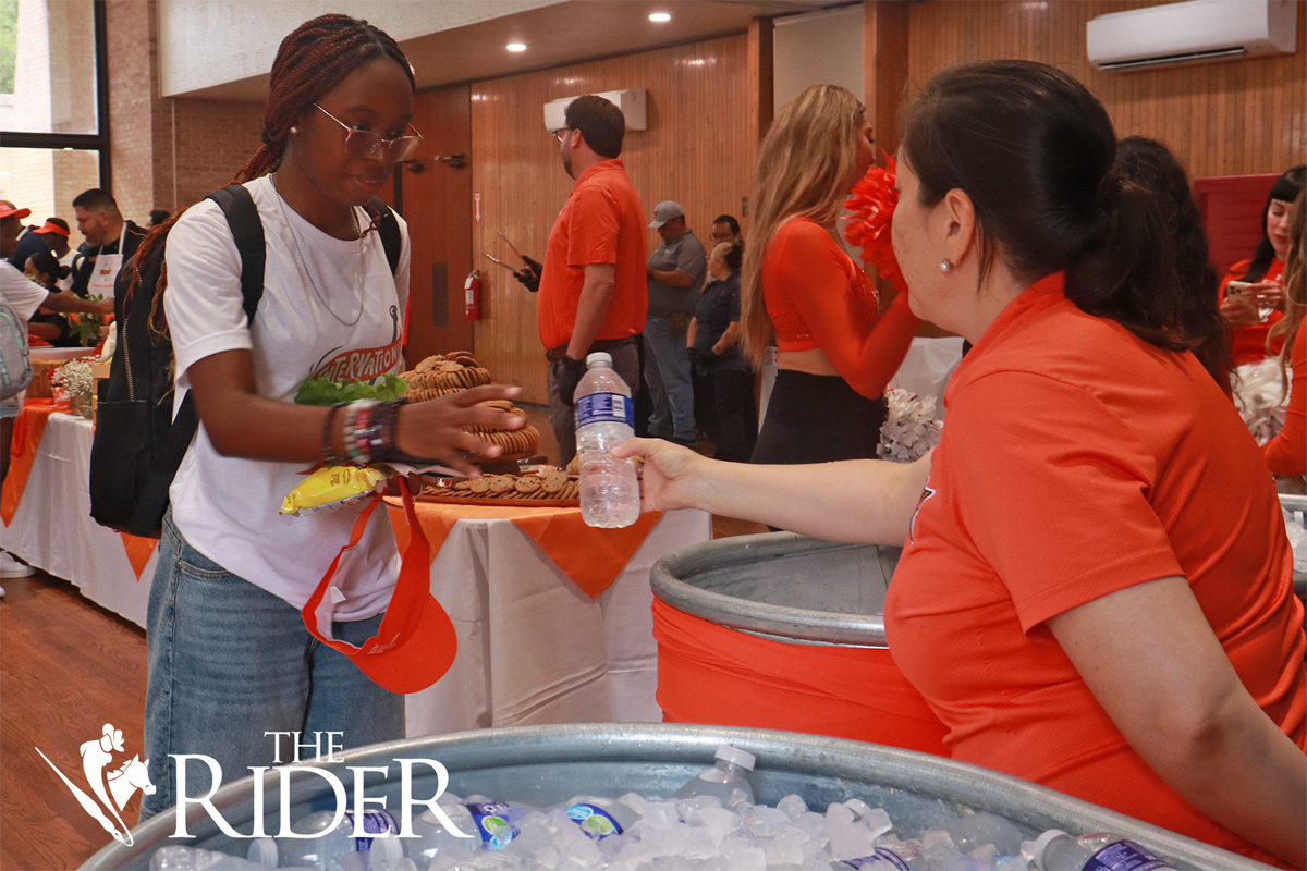 UTRGV Event Manager Dalyn Ruiz hands a water bottle to biology junior Ekemini Akpabio during Picnic with the President Wednesday afternoon in the University Ballroom on the Edinburg campus. Angel Ballesteros/THE RIDER