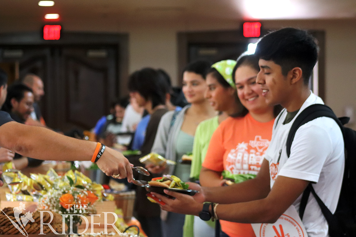 Environmental science freshman Cristopher Guevara receives a burger during Picnic with the President Thursday in the PlainsCapital Bank El Gran Salón on the Brownsville campus. Venisha Colón/ THE RIDER