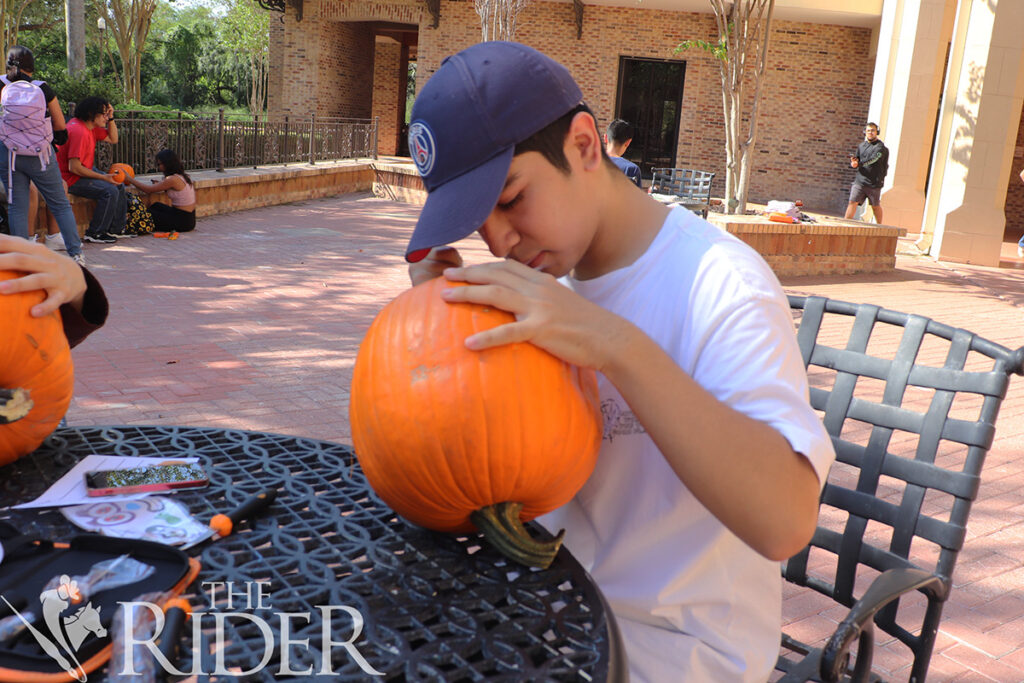 Alfonso García, estudiante de primer año de seguridad cibernética, carva el interior de su calabaza durante el concurso de tallado de calabazas el miércoles afuera del Student Union en el campus de Brownsville. Silvana Villarreal/THE RIDER