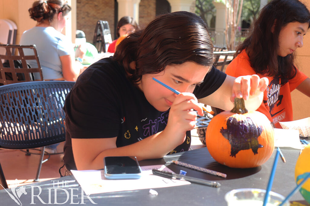 Edna Desilos, estudiante de tercer año de inglés, pinta su calabaza para el concurso de tallado de calabazas que se realizó el miércoles afuera del Student Union en el campus de Brownsville. Silvana Villarreal/THE RIDER