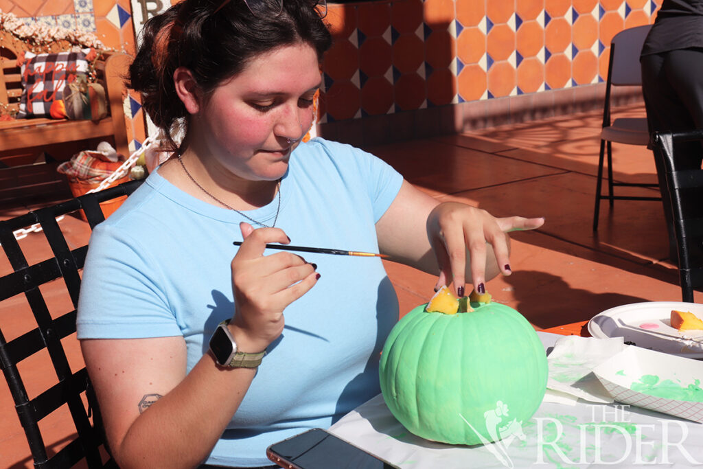 Cassandra Alaniz, estudiante de último año de educación, pinta su calabaza con temática de Mike Wazowski para el concurso de tallado de calabazas el miércoles afuera del Student Union en el campus de Brownsville. Silvana Villarreal/THE RIDER