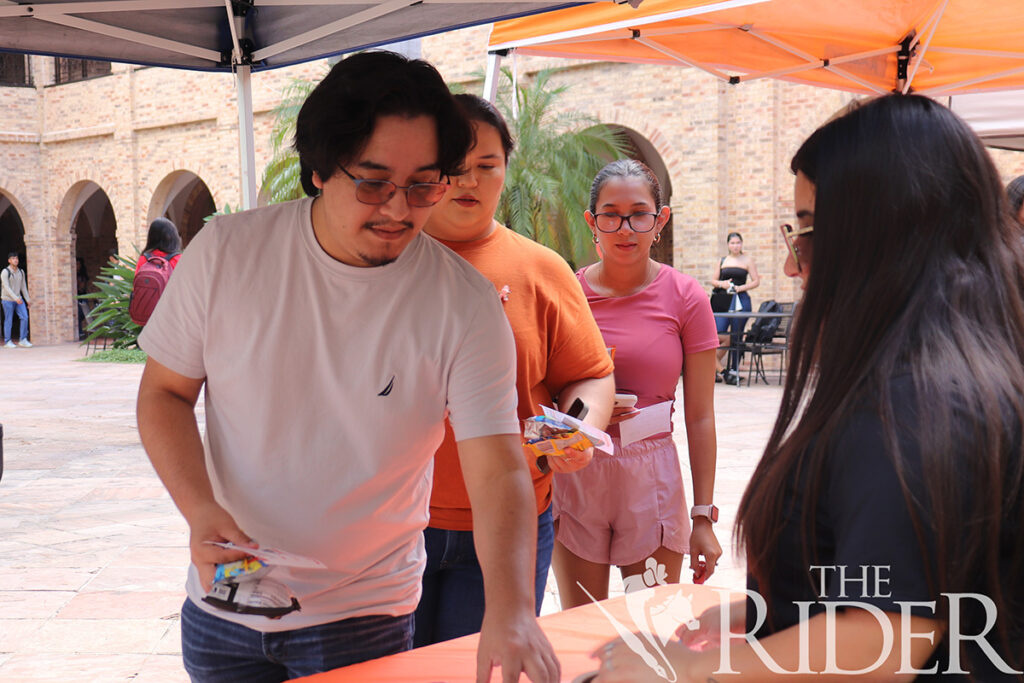 Chemistry senior Marcus Escobar visits the SGA tabling event for information, snacks and merchandise Tuesday in the Main Building Courtyard on the Brownsville campus. Silvana Villarreal/THE RIDER