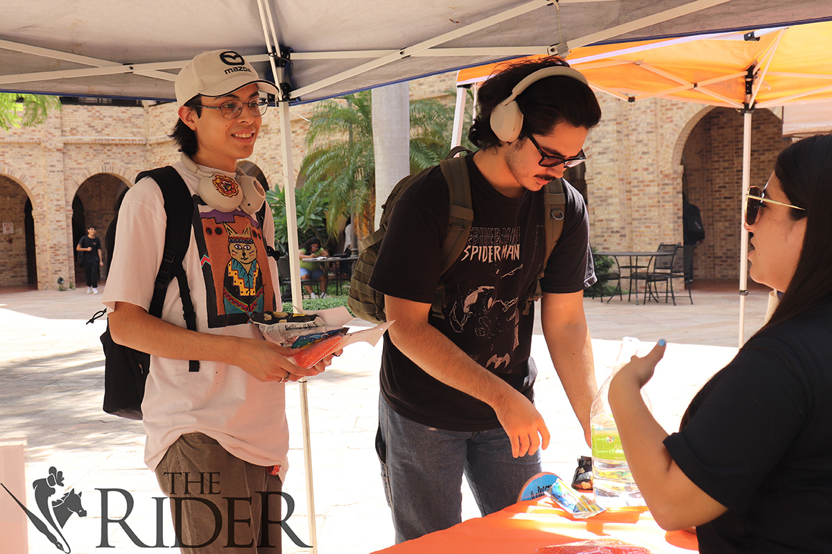 Criminal justice senior Brianna Rodriguez (far right) asks Nathan Floyd, computer science senior, and Francisco Benavides, computer science junior, to complete a survey and gives away merchandise Tuesday in the Main Building Courtyard on the Brownsville campus. Silvana Villarreal/THE RIDER